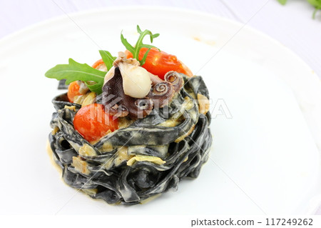 Black spaghetti. Black seafood pasta in white plate on black background with copy space. 117249262