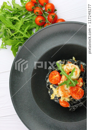 Black spaghetti. Black seafood pasta in white plate on black background with copy space. 117249277