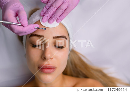 A procedure for mechanical or manual face cleansing by a beautician. Professional skin peeling. Hygiene for the skin A procedure for mechanical or manual face cleansing by a beautician. Professional skin peeling. Hygiene for the skin 117249634