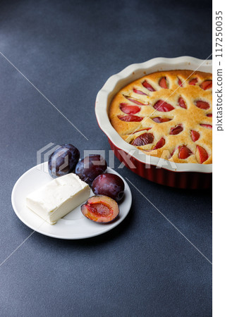 Freshly Baked Plum Cake With Butter and Plums on a Dark Background 117250035