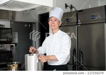 Young asian male chef preparing food in the kitchen Young asian male chef preparing food in the kitchen 117250279