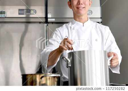 Young asian male chef preparing food in the kitchen Young asian male chef preparing food in the kitchen 117250282