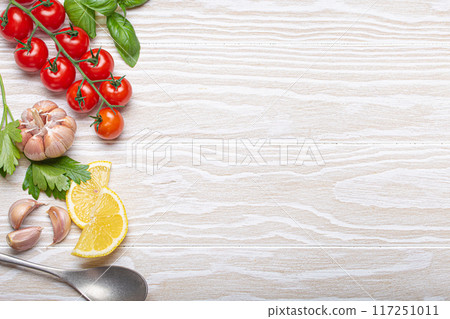 Healthy food ingredients composition with fresh cherry tomatoes, herbs, garlic cloves, lemon wedges and spoon on white wooden shabby background, overhead shot with copy space Healthy food ingredients composition with fresh cherry tomatoes, herbs, garlic cloves, lemon wedges and spoon on white wooden shabby background, overhead shot with copy space 117251011