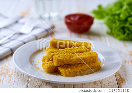 Fried fish sticks or fish fingers on a wooden table.   Snack food. 117251158