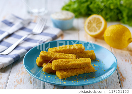 Crispy breaded deep fried fish fingers with lemon and tartar sauce on wooden table. Crispy breaded deep fried fish fingers with lemon and tartar sauce on wooden table. 117251163