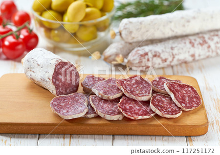 traditional Spanish salami fuet sausage or dry sausage cut in slices in a kitchen table. 117251172