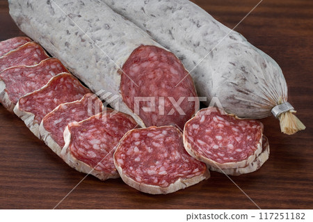 Slices of delicious spanish sausage fuet on a wooden table, selective focus. 117251182