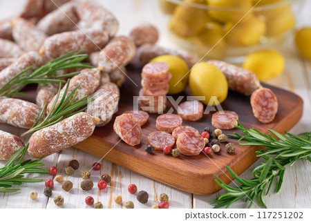 chorizo mini, spicy pork fermented dry cured salami sausages with spices and olives  on a wooden table. 117251202