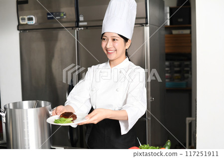 Young asian female chef serving meat dishes Young asian female chef serving meat dishes 117251911