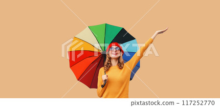 Autumn beautiful happy cheerful young woman holds colorful umbrella enjoys new season in sweater Autumn beautiful happy cheerful young woman holds colorful umbrella enjoys new season in sweater 117252770