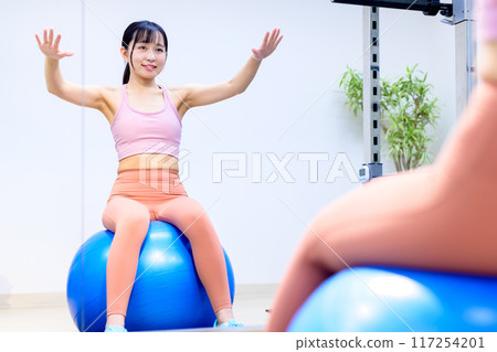 年輕女子在健身房騎平衡球、飲食、私人健身房、肌肉訓練女孩、修剪 年輕女子在健身房騎平衡球、飲食、私人健身房、肌肉訓練女孩、修剪 117254201