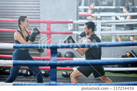 Boxing, training and exercising with a healthy, fit and active female boxer and her male coach or personal trainer in the gym. Workout, fitness and exercise with an athlete and her sports instructor Boxing, training and exercising with a healthy, fit and active female boxer and her male coach or personal trainer in the gym. Workout, fitness and exercise with an athlete and her sports instructor 117254439