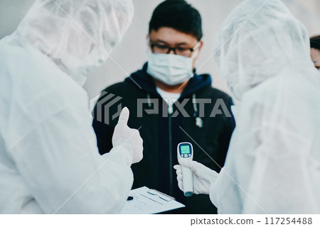 Negative covid test and thumbs up for young man from healthcare worker after testing for virus. Medical professionals in hazmat suits taking temperature tests during disease outbreak or pandemic Negative covid test and thumbs up for young man from healthcare worker after testing for virus. Medical professionals in hazmat suits taking temperature tests during disease outbreak or pandemic 117254488