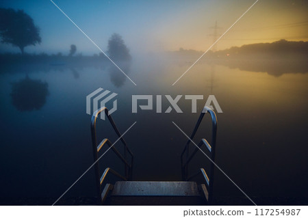 stairs into lake at night with fog 117254987
