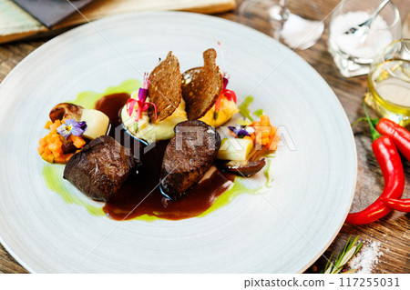 Deer tenderloin. Truffle-potato puree, porcini mushrooms, baked leek and carrot, juniper bread, port wine sauce. Delicious healthy traditional food served for lunch in modern gourmet restaurant 117255031