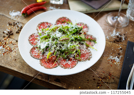 Beef carpaccio. Borettane onion, sun-dried tomato, truffle dressing, arugula salad, parmesan cheese. Italian traditional antipasti snacks served for lunch with wine in modern gourmet restaurant 117255045