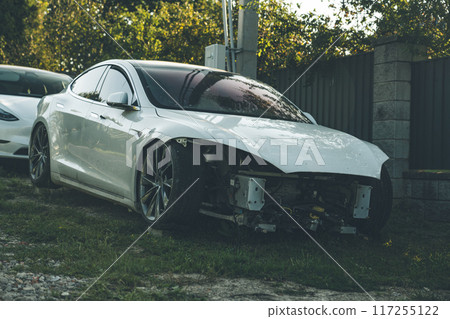 A broken Tesla model s without headlights stands in the village A broken Tesla model s without headlights stands in the village 117255122
