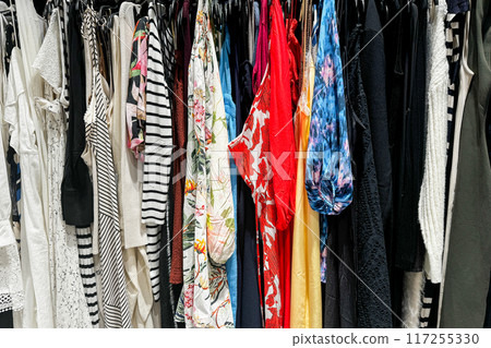 A colorful assortment of various clothing items hanging on a rack in a store A colorful assortment of various clothing items hanging on a rack in a store 117255330