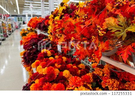 A store aisle filled with vibrant artificial autumn flowers and decorations A store aisle filled with vibrant artificial autumn flowers and decorations 117255331