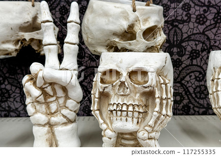 Halloween-themed skeletal decorations, including a skull planter and a hand making a peace sign Halloween-themed skeletal decorations, including a skull planter and a hand making a peace sign 117255335