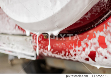 At the sink, the foam flows down and drips from the car onto the floor of the box. The car was driven to the sink to clean the dirt and dust after the road. The concept of contactless car wash. At the sink, the foam flows down and drips from the car onto the floor of the box. The car was driven to the sink to clean the dirt and dust after the road. The concept of contactless car wash. 117255559