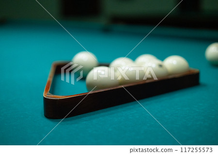 A man's hands stack billiard balls into a pyramid on a billiard table. A man collects balls into a billiard triangle to start a new game of billiards. 117255573