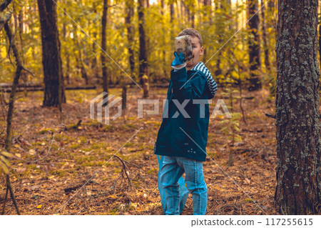 Cleaning the forest from garbage waste. A child with a garbage bag collects garbage in the forest. The problem of forest pollution with waste, an environmental disaster. 117255615