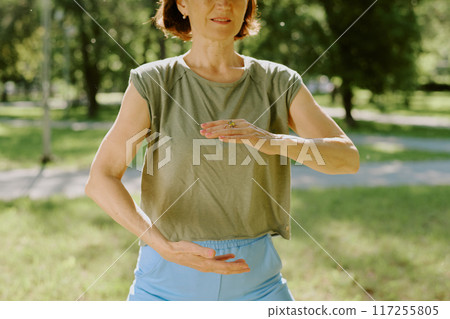 Medium close up of sporty senior woman during pose for improving coordination in park 117255805