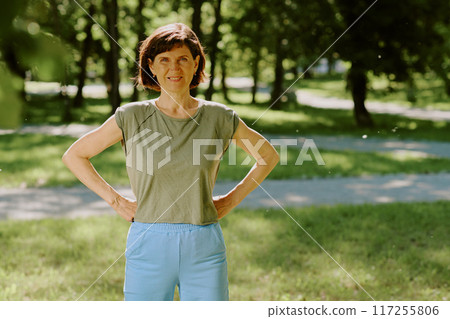 Portrait of smiling brunette woman dressed in cotton sportswear looking directly at camera while having open air workout 117255806