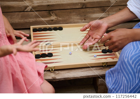 A mother and daughter spend quality time baking croissants together in a cozy kitchen. The little girl thoughtfully arranges baked goods while learning the art of cooking. 117256442