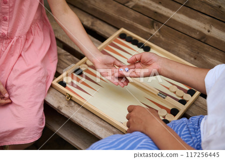 A mother and daughter spend quality time baking croissants together in a cozy kitchen. The little girl thoughtfully arranges baked goods while learning the art of cooking. 117256445