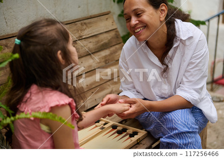 A mother and daughter spend quality time baking croissants together in a cozy kitchen. The little girl thoughtfully arranges baked goods while learning the art of cooking. A mother and daughter spend quality time baking croissants together in a cozy kitchen. The little girl thoughtfully arranges baked goods while learning the art of cooking. 117256466