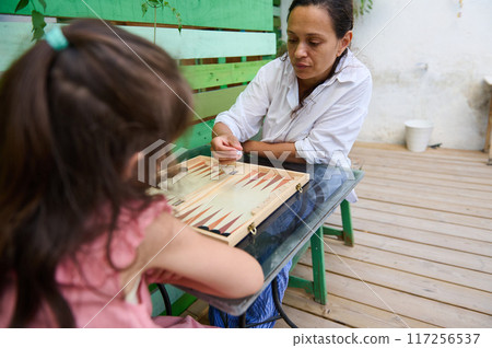 Mother and daughter playing backgammon together at home 117256537