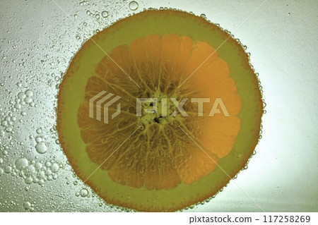 Slice of orange fruit in water on white background. Orange close-up in liquid with bubbles. Slice of red ripe orange in water. Macro image of fruit in water 117258269