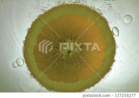 Slice of orange in sparkling water. Orange fruit slice covered by bubbles in carbonated water. Orange slice in water with bubbles 117258277