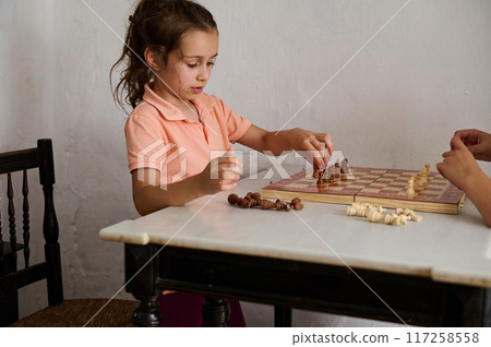 Young girl playing chess with an adult at home 117258558