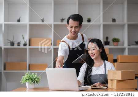 A couple of online sellers work together to take online orders and pack products for delivery to customers. A couple of online sellers work together to take online orders and pack products for delivery to customers. 117258913