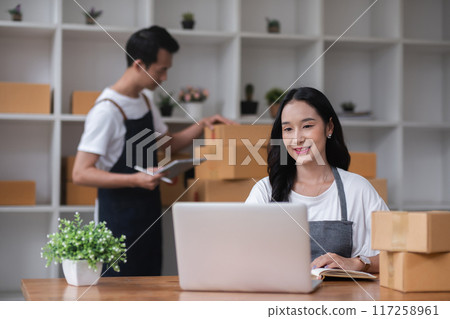 A couple of online sellers work together to take online orders and pack products for delivery to customers. A couple of online sellers work together to take online orders and pack products for delivery to customers. 117258961