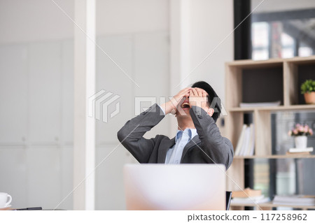Unhappy young businessman feeling bored or disappointed while sitting in the office Distracted male employee feeling tired from monotonous work 117258962