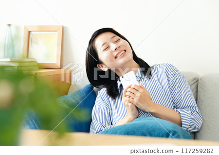 A woman looking at her smartphone in the living room 117259282