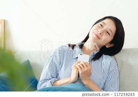 A woman looking at her smartphone in the living room A woman looking at her smartphone in the living room 117259283