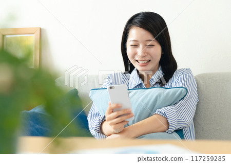 A woman looking at her smartphone in the living room 117259285