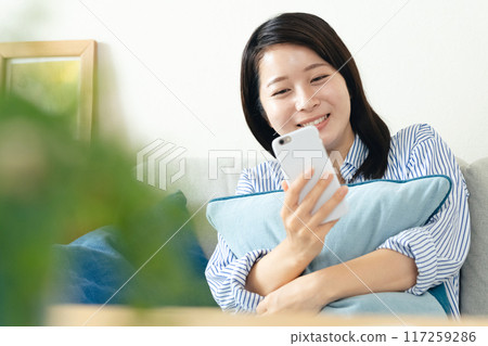A woman looking at her smartphone in the living room 117259286