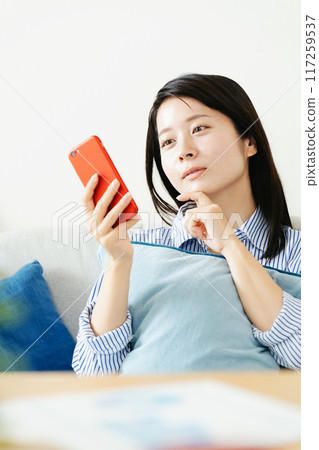 A woman looking at her smartphone in the living room A woman looking at her smartphone in the living room 117259537