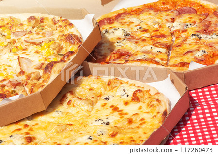 Three different pizzas on the background of a checkered white and red tablecloth. Three different pizzas on the background of a checkered white and red tablecloth. 117260473