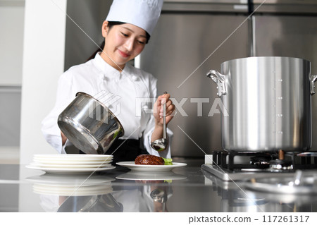 Young Asian female chef serving food on a plate 117261317