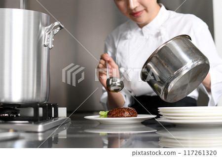 Young Asian female chef serving food on a plate Young Asian female chef serving food on a plate 117261320