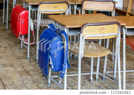 Retro desks and blue and red school bags in an old classroom Retro desks and blue and red school bags in an old classroom 117261861