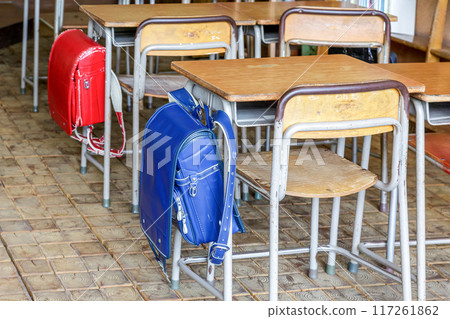 Retro desks and blue and red school bags in an old classroom Retro desks and blue and red school bags in an old classroom 117261862