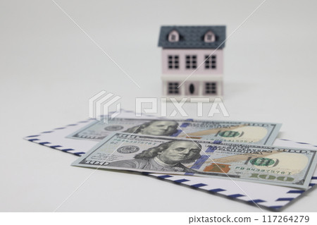 Banknotes in a white envelope and a toy house, funds for the purchase of real estate. Banknotes in a white envelope and a toy house, funds for the purchase of real estate. 117264279